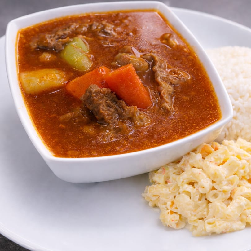 Beef stew with carrots, potatoes, and celery, served with white rice and macaroni salad.