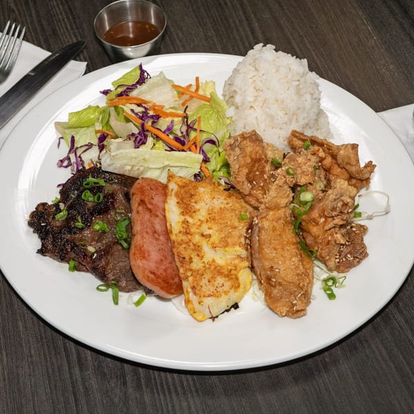 A plate of grilled meat, fried chicken, spam, fried fish, rice, and salad.